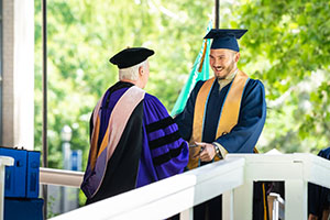 A student receives their diploma during commencement.