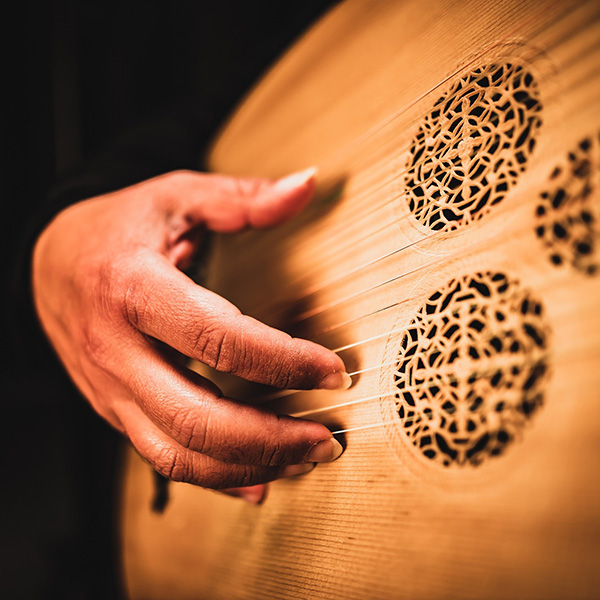 Close up of a hand playing the 13 string Oud.