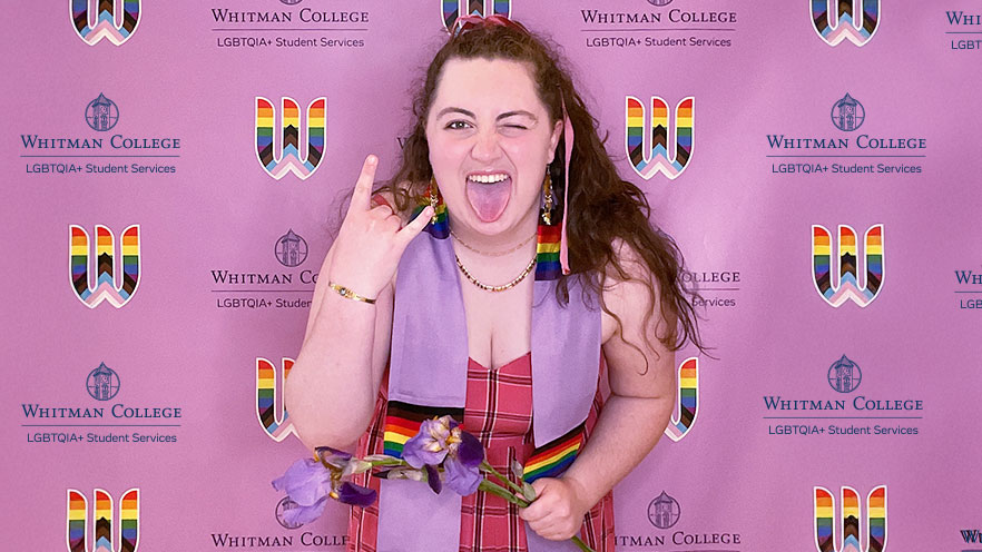 Zoe Perkins wearing a graduation stole posing in front of a colorful backdrop.