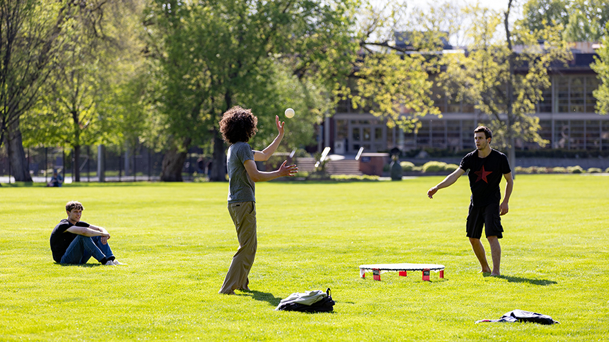 Sunny afternoon at Ankeny Field with students playing spikeball