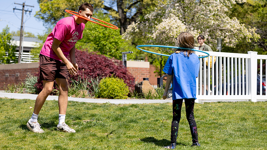 Whitman College student playing hula hoop with an elementary student.
