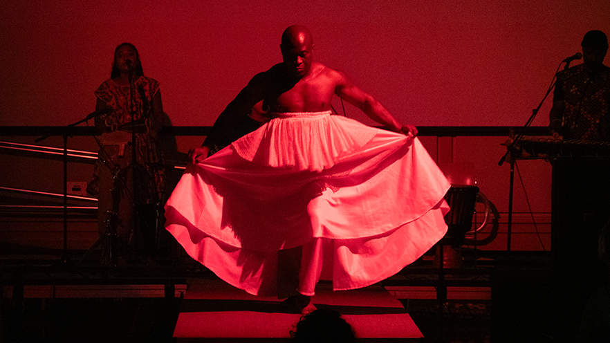 Individual on stage showcasing African fashion and performance to honor and celebrate Africa’s cultural richness.