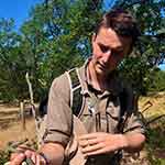 Frazer Moore looks down at a snake in his hand