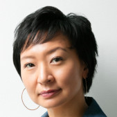 Woman looking to the camera, with short hair and hoop earrings