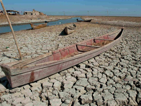 Photo of a wooden boat on sun-scorched, cracked earth