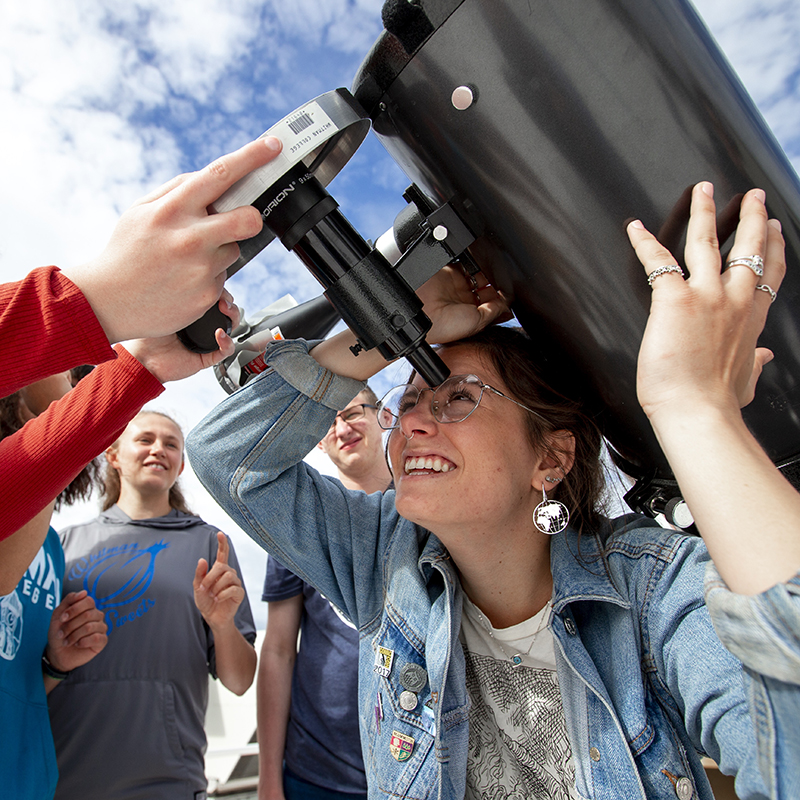 Students with a large telescope outdoors.