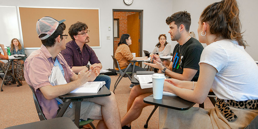 Matt Bost has a discussion in a rhetoric course with three students.