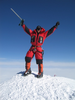 Outdoor Program Director, Brien Sheedy, exuberantly summiting a snow-covered peak.