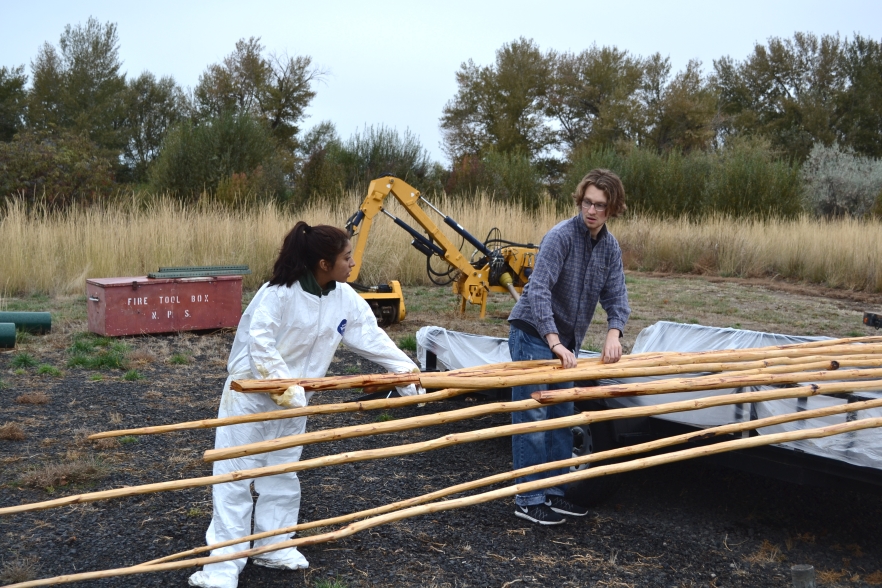 Two Whitman volunteers handle raw timber at Make a Difference Day.