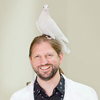 Portrait of Professor Walter Herbranson with a white pigeon sitting on his head