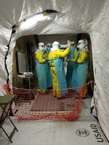 Members of the U.S. Public Health Service Commissioned Corps confer in the MMU's 'Hot Zone' after donning Personal Protective Equipment.