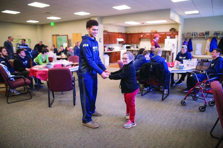 Jaron Kirkley ’20 dances with Cynthia—a resident at HopeTree Family Services in Salem,  Virginia—during the team’s community outreach before their Final Four matchup.