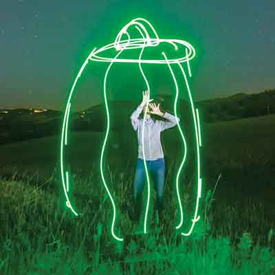 Laura Krantz in a field at night with a flying saucer effects added to the image