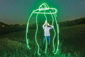 Laura Krantz in a field at night with a flying saucer effects added to the image