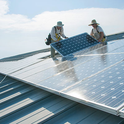 Workers installing solar panels on a roof