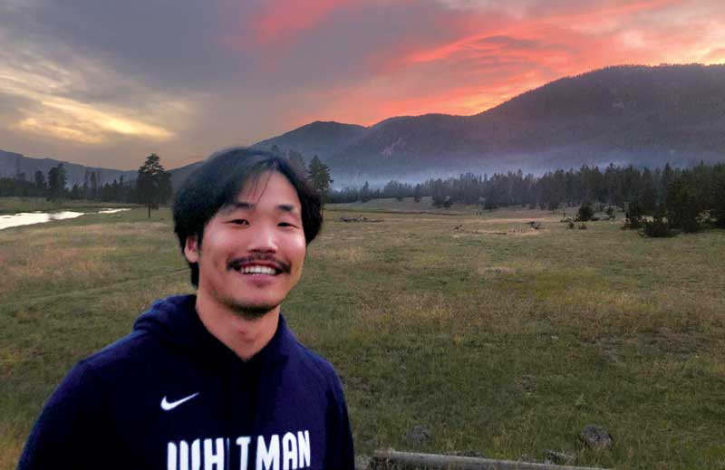 Eric Lim outside with a sunset behind the mountains.