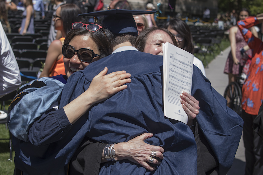 Associate Professor of Sociology Helen Kim (left) and Associate Professor of Anthropology and Interdisciplinary Studies Suzanne Morrissey hug a newly-minted Whitman graduate. 