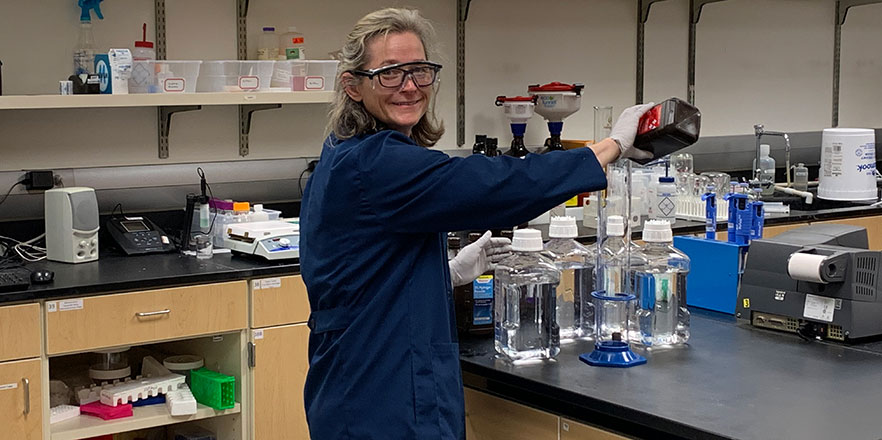 Sarah Kirk '95 works in a lab mixing chemicals for hand sanitizer at Willamette University.