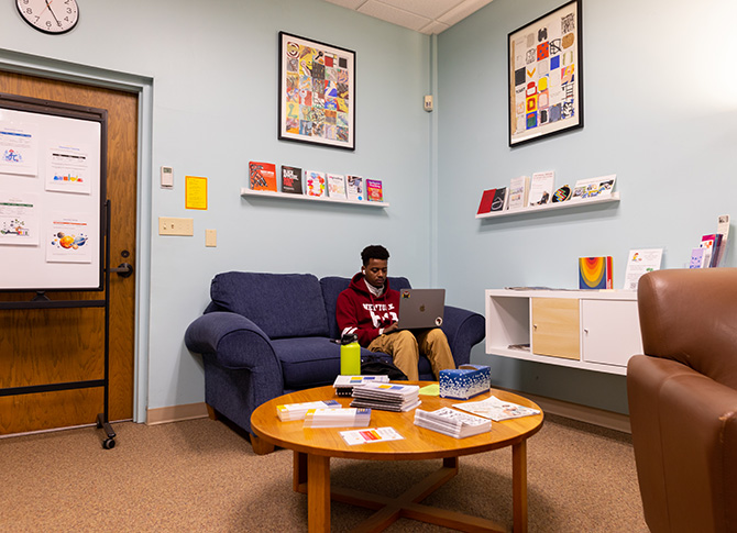 Student sitting on a couch at the ARC while working on their computer.