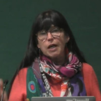 Woman with dark hair, glasses, and a colorful shawl