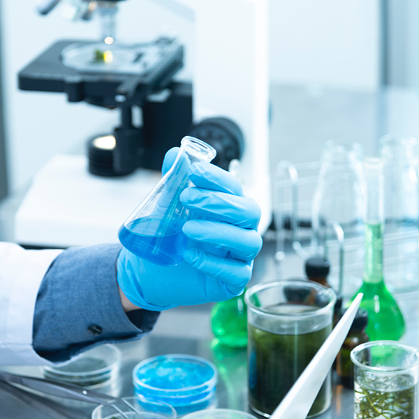 Gloved hands holding a vial in a lab.