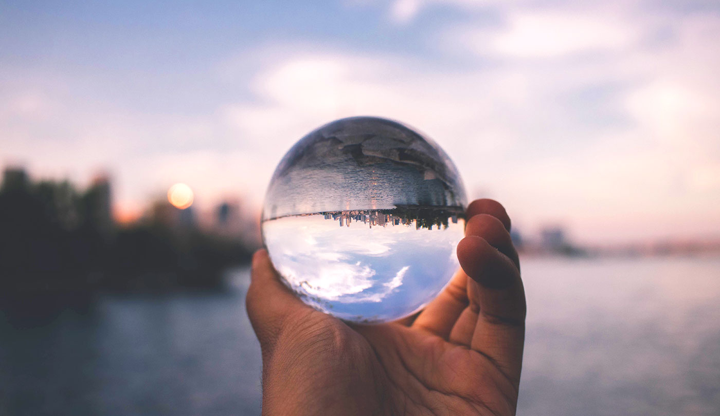 Looking at a city through a glass sphere held in a hand.