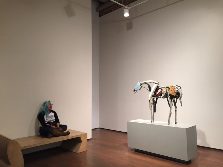 Brenna TwoBears '17, sitting, observes art in a gallery