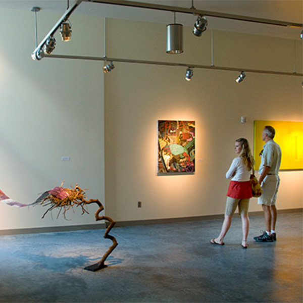 Two people looking at a painting in an art gallery.