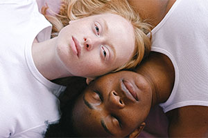 Two persons lying next to each other; one is black and one is white.