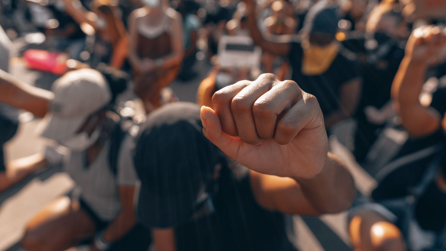 Fist raised in awareness from people in a gathering.