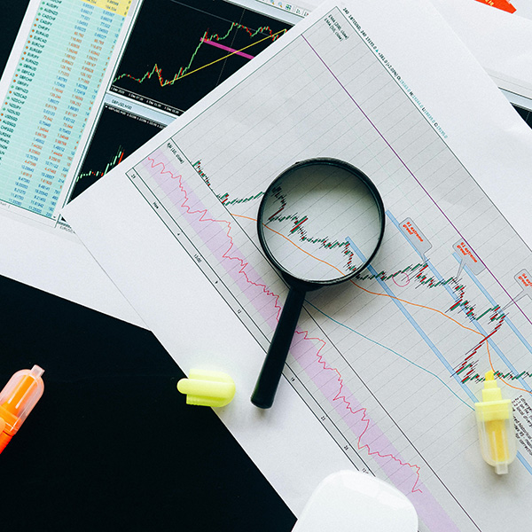 Image of statistical papers laid out with highlighters and magnifying glass laying on top.