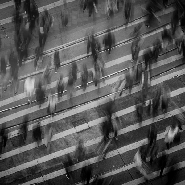 Blurred black and white birds eye view image of people crossing the street.
