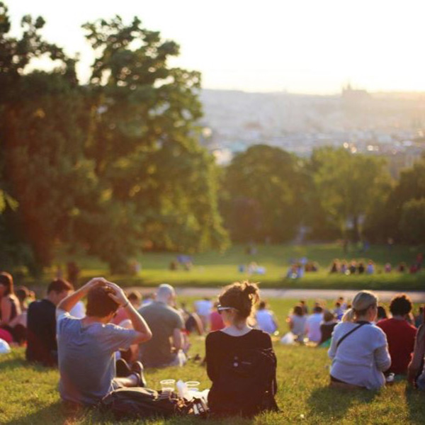 A couple sitting on a hill with other groups of people taking in the sun.