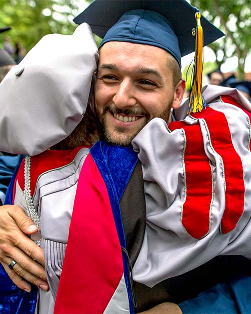A graduate hugging a professor after the commencement ceremony.