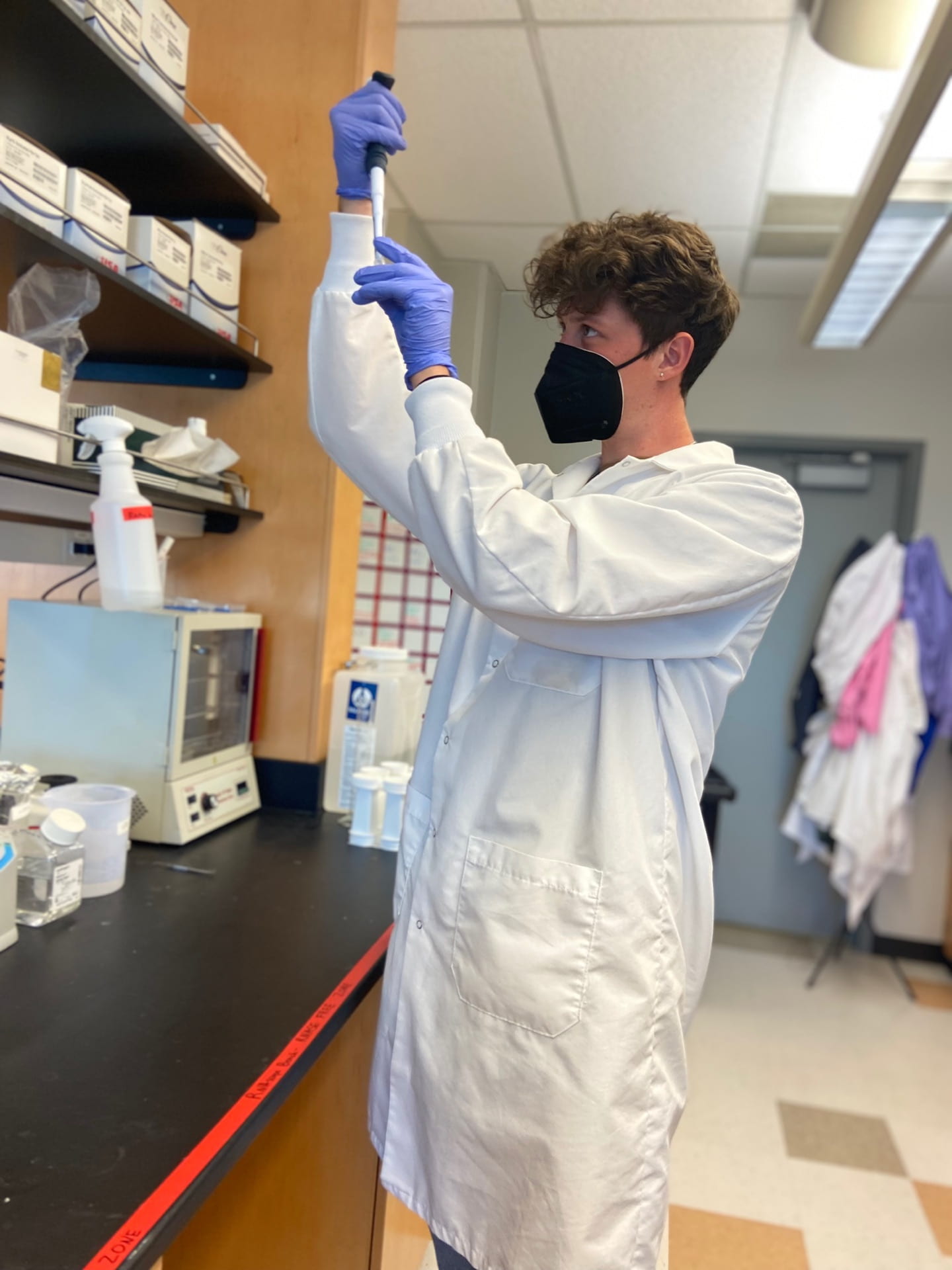 Riley Kraft holding up a RNA scope in the Zelikowsky lab.