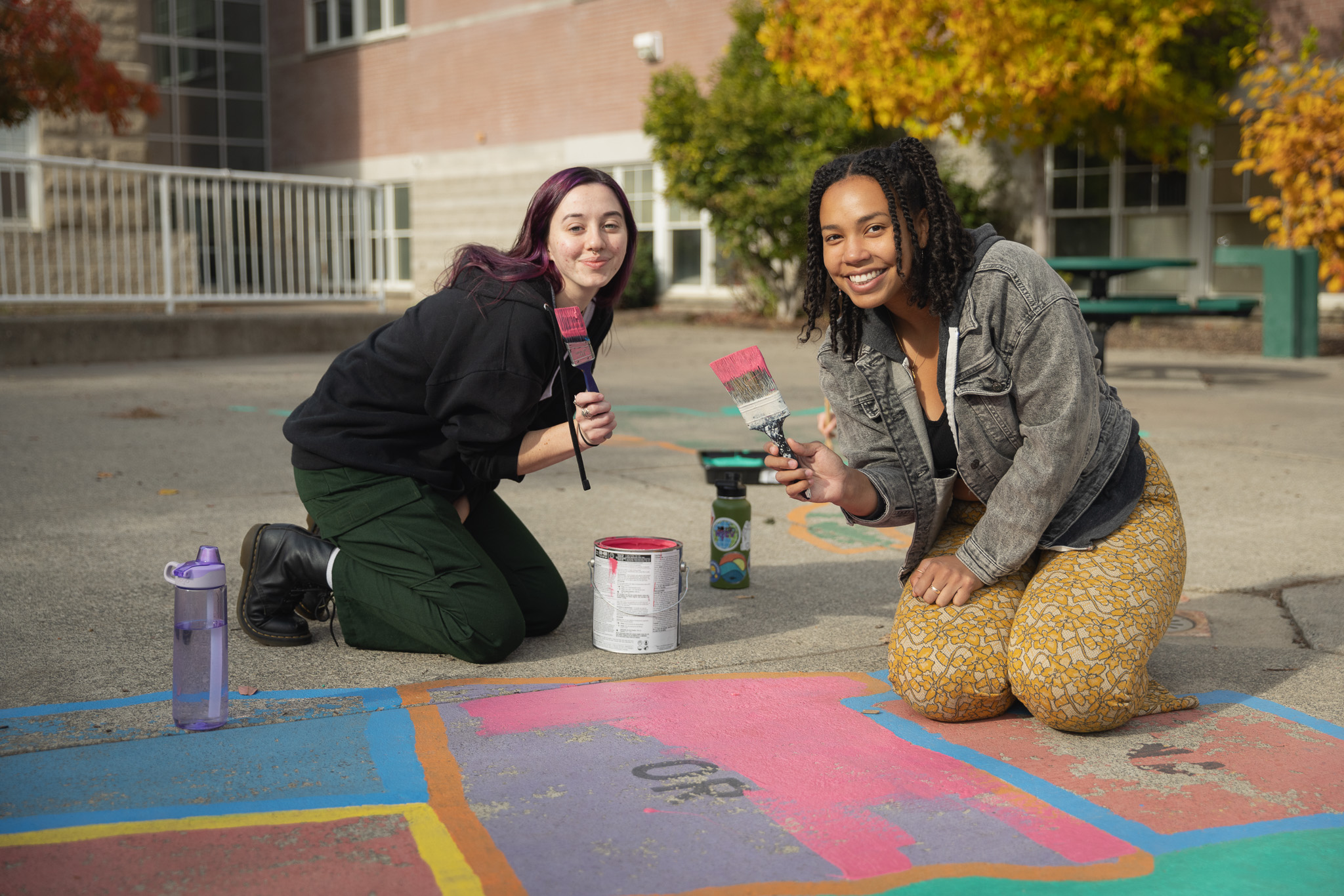 Community Engagement Volunteers Alanna Sherman '24 and Devon Player '23 Repainting a School Mural