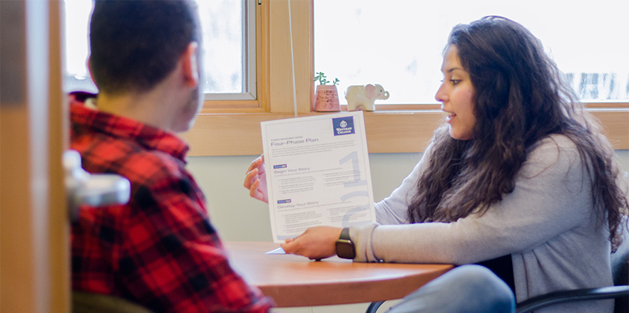A student examines a printed copy of the Four Phase Plan with an advisor from the Student Engagement Center.