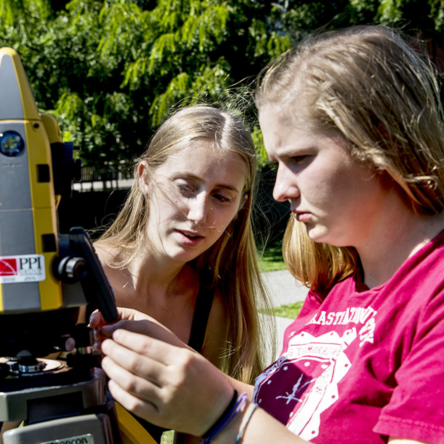 Two students collaborating outdoors in the sunshine.