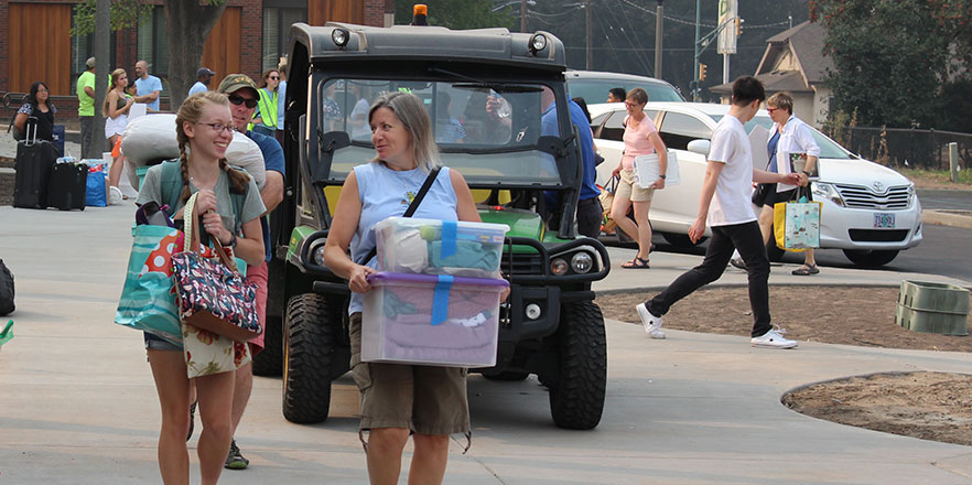 A student and her mother carry items during move-in.