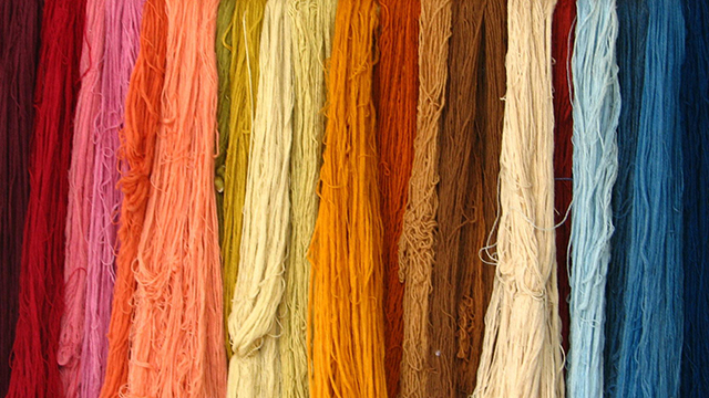 A variety of different colored threads hanging in rows together.
