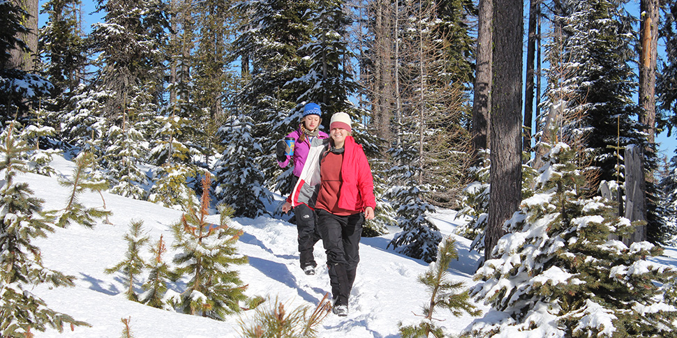 Two Whitman student walking through the forrest covered in snow.