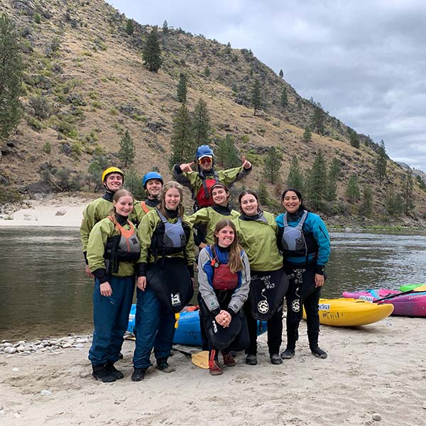 A group of kayakers on the river bank posing for the camera.