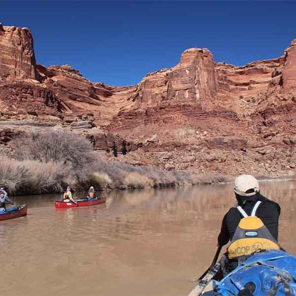 A canoe instructor guding canoes down a river..