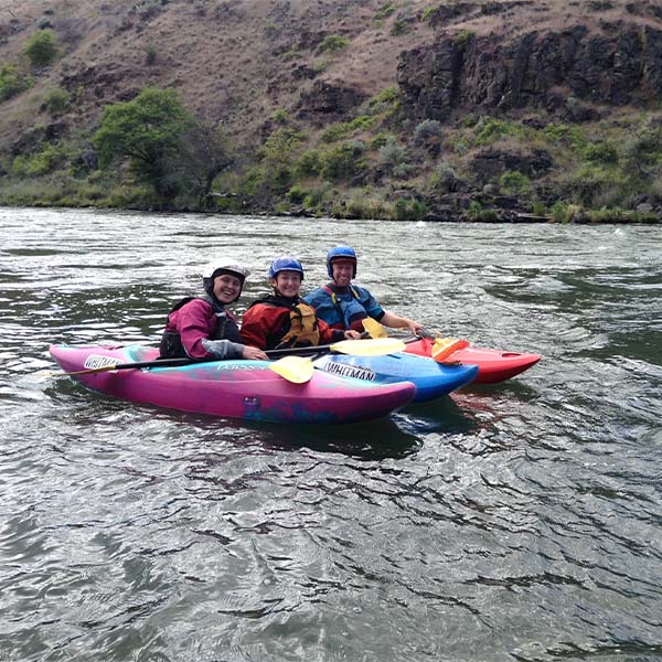 Three kayakers smiling in the water.