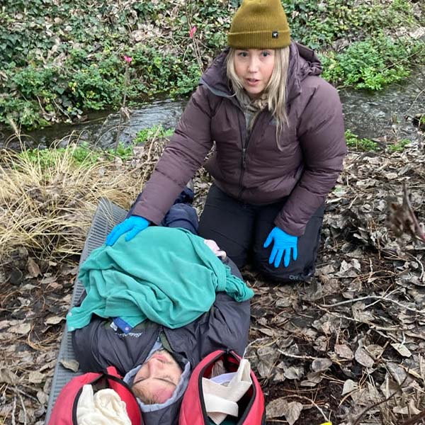 A student practicing wilderness first responder skills on another student.