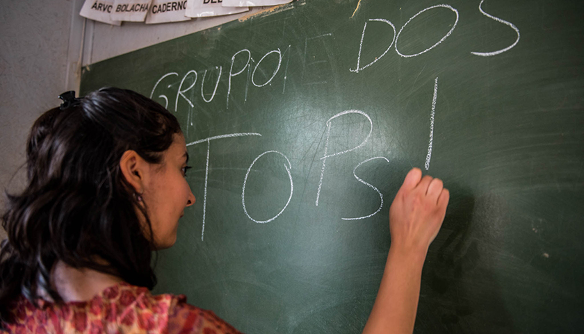Ludmila De Brito '18 writes on a chalkboard in an elementary school classroom. 