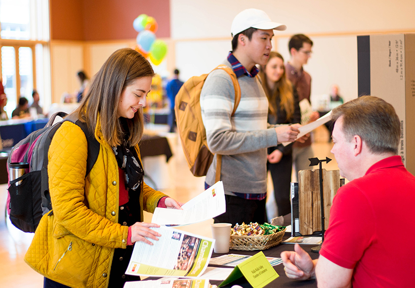 A student picks up promotional materials from the Walla Walla Valley Chamber of Commerce table at the 2018 Pop Up Job Fair in the Reid Young Ballroom. 