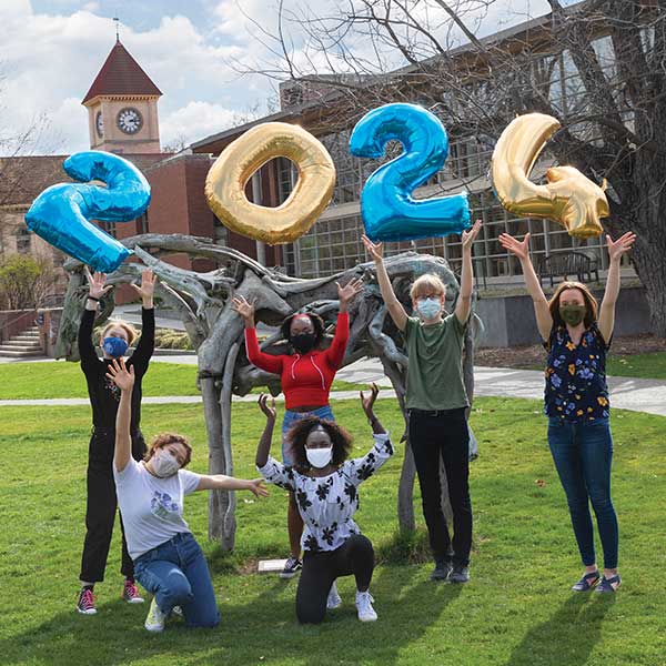 Students holding "2024" balloons outside.