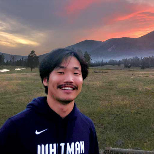 Eric Lim outside with a sunset behind the mountains.