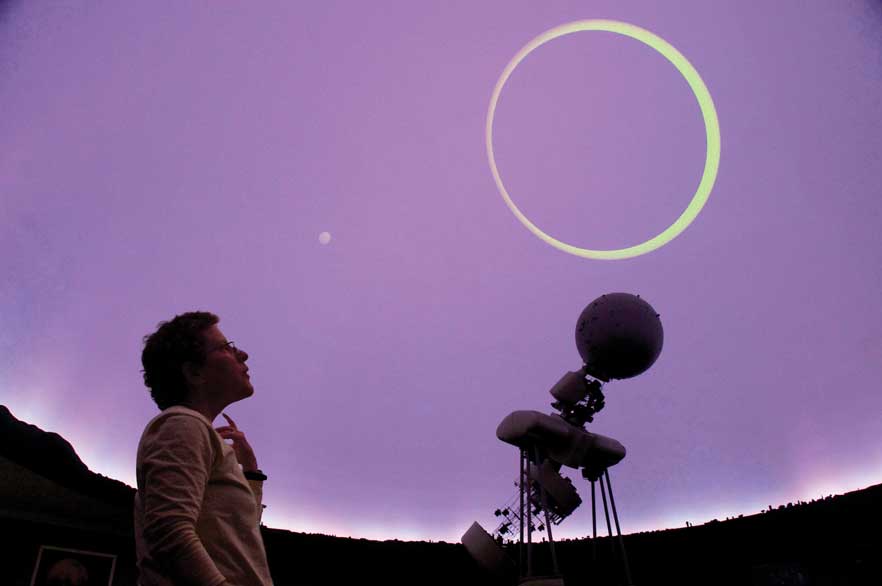 Andrea Dobson looking at a projection of a circle emitted from a telescope.